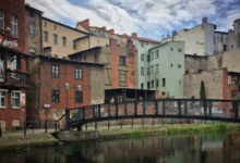 Rzeźba linoskoczka nad rzeką i kamienice nad wodą