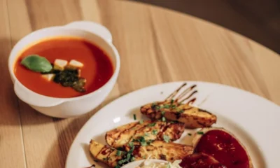 Zupa pomidorowa z bazylią i talerz pieczonych ćwiartek ziemniaków z surówką na drewnianym stole